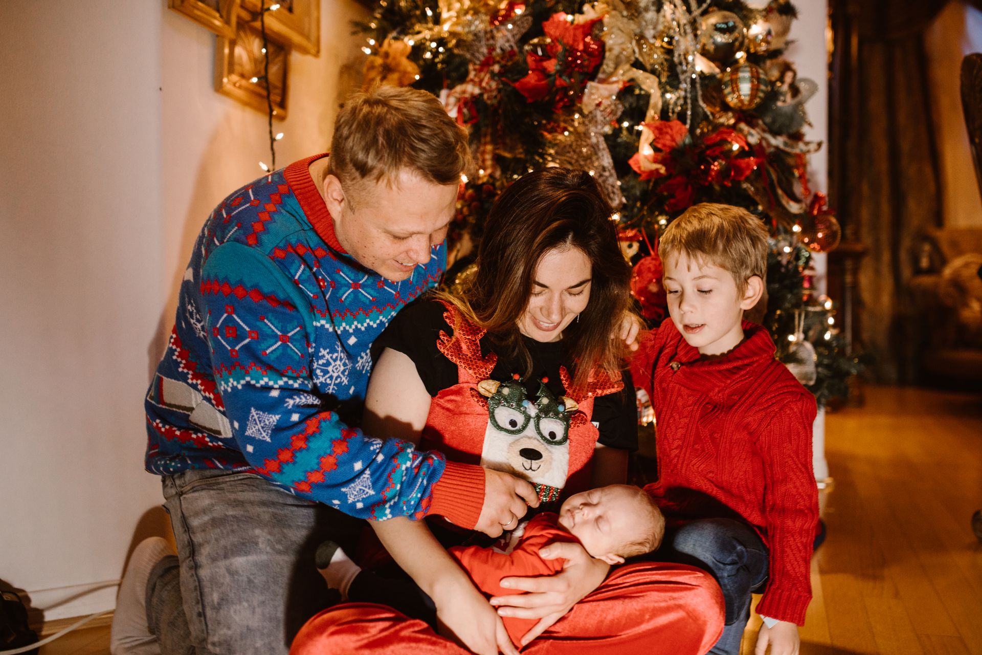 A joyful family gathers around a decorated Christmas tree during festive celebrations.
