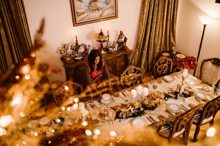 Woman Putting Plates On Table At Christmas