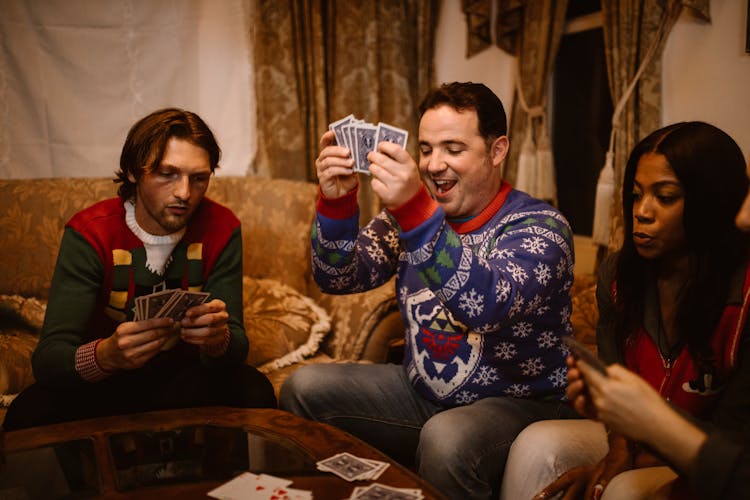 Group Of People Playing Cards In The Living Room