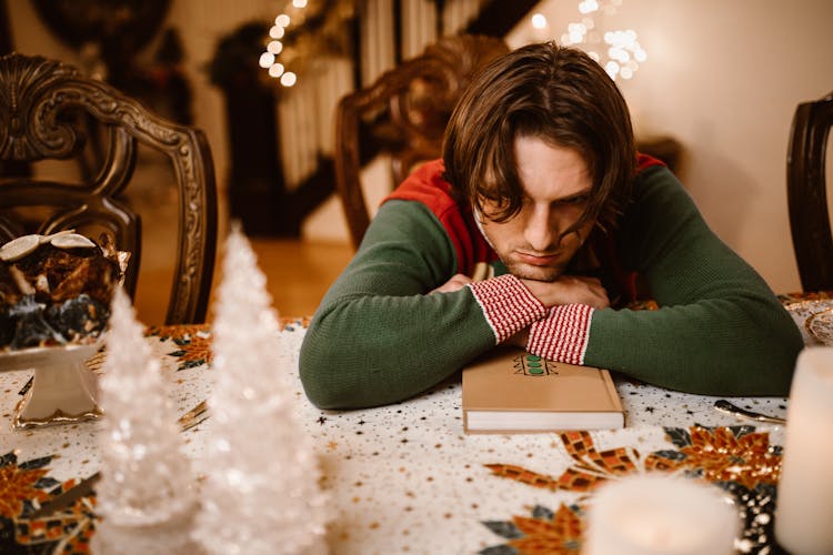 A Man In Green Sweater Lying On The Table