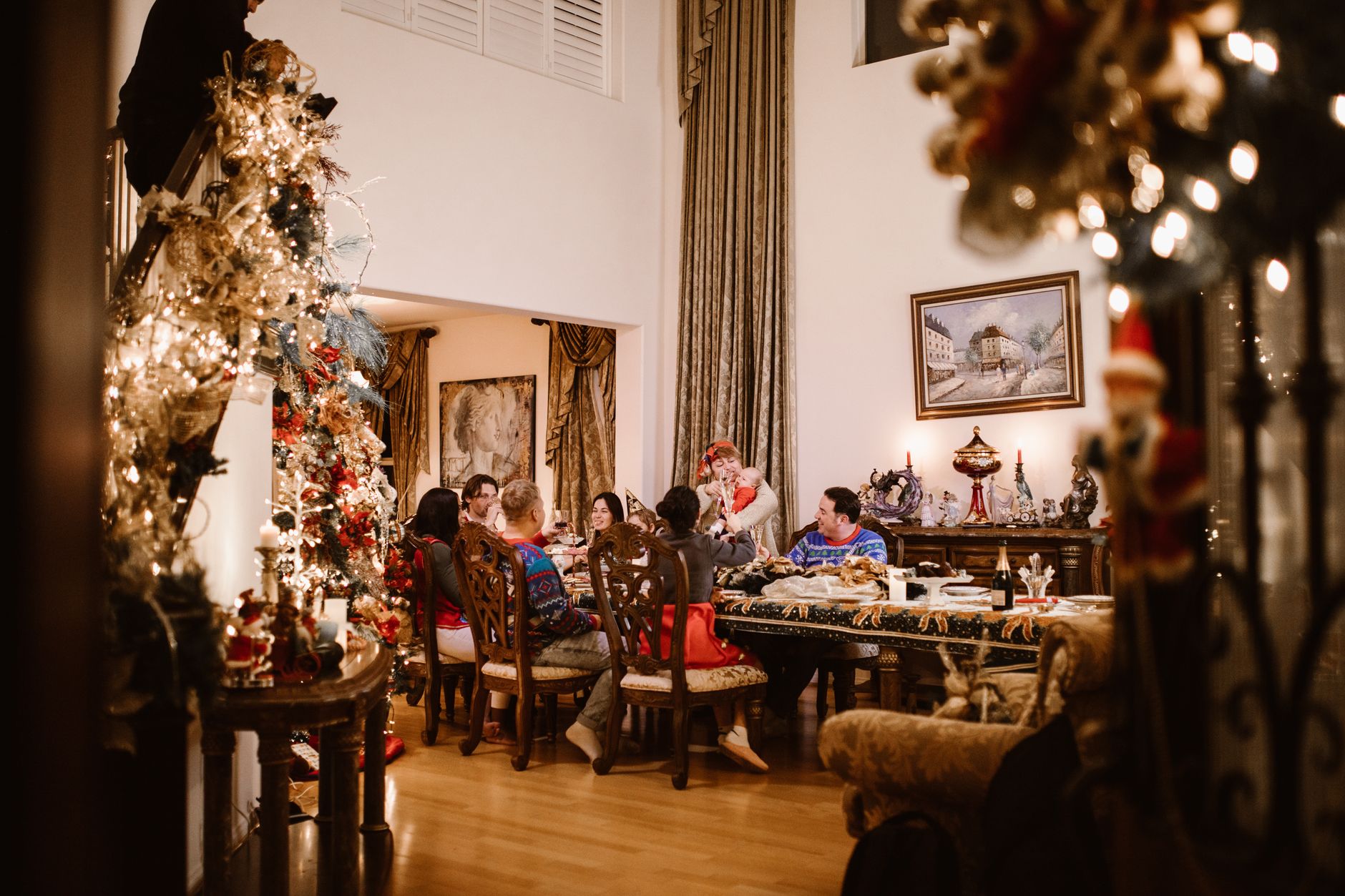 A cheerful family enjoying Christmas dinner in a warmly decorated home with a beautifully lit tree.