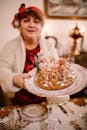 Woman in White Long Sleeve Shirt Holding White and Gold Round Cake