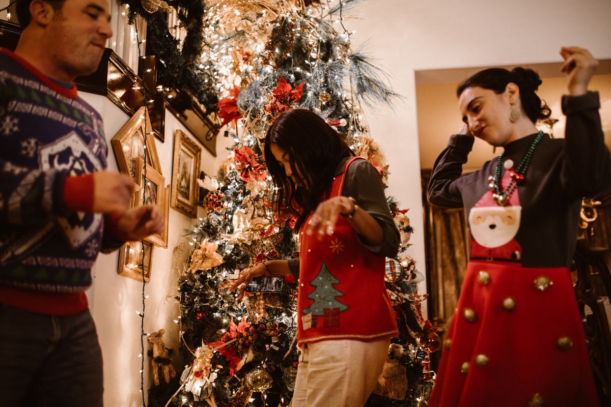 Friends dancing beside a decorated Christmas tree at a holiday party
