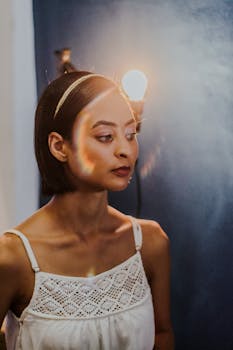 A thoughtful woman in a white top indoors, with artistic light reflections.