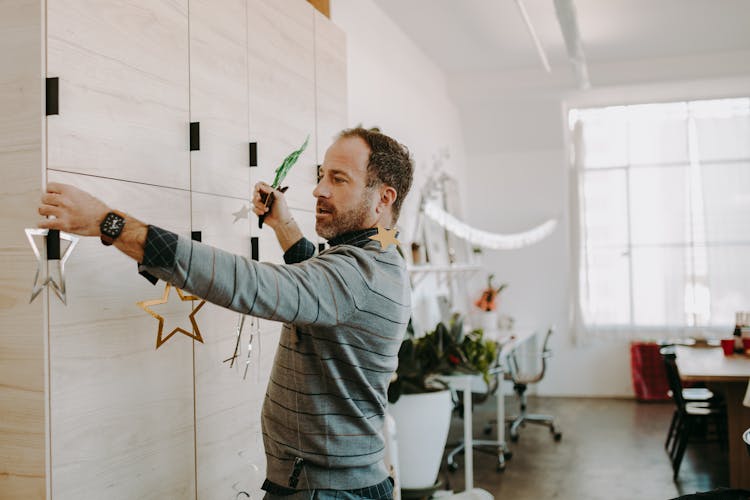 Man In Gray Sweater Putting Up Decorations