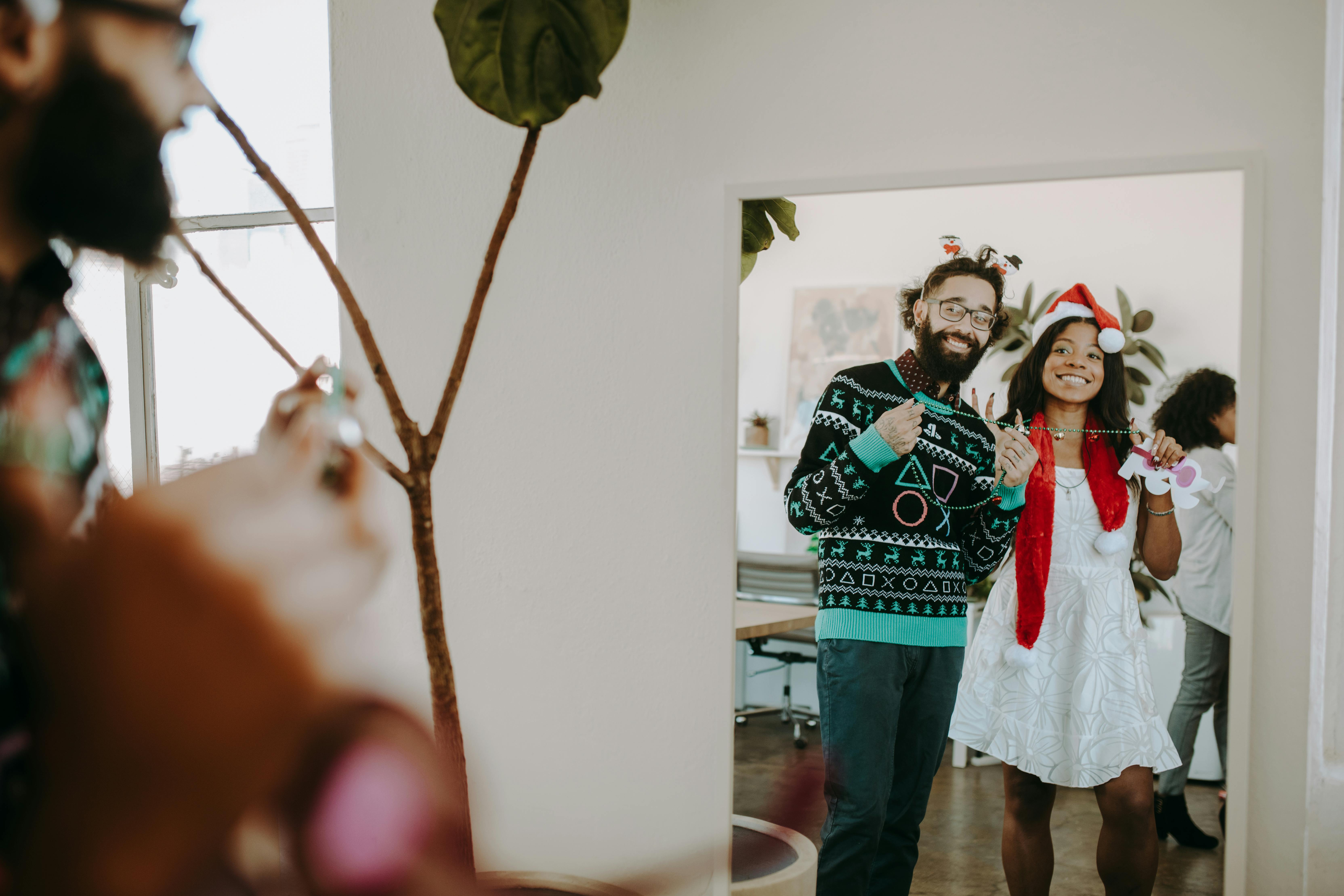 Happy colleagues in festive attire enjoying office Christmas party indoors.