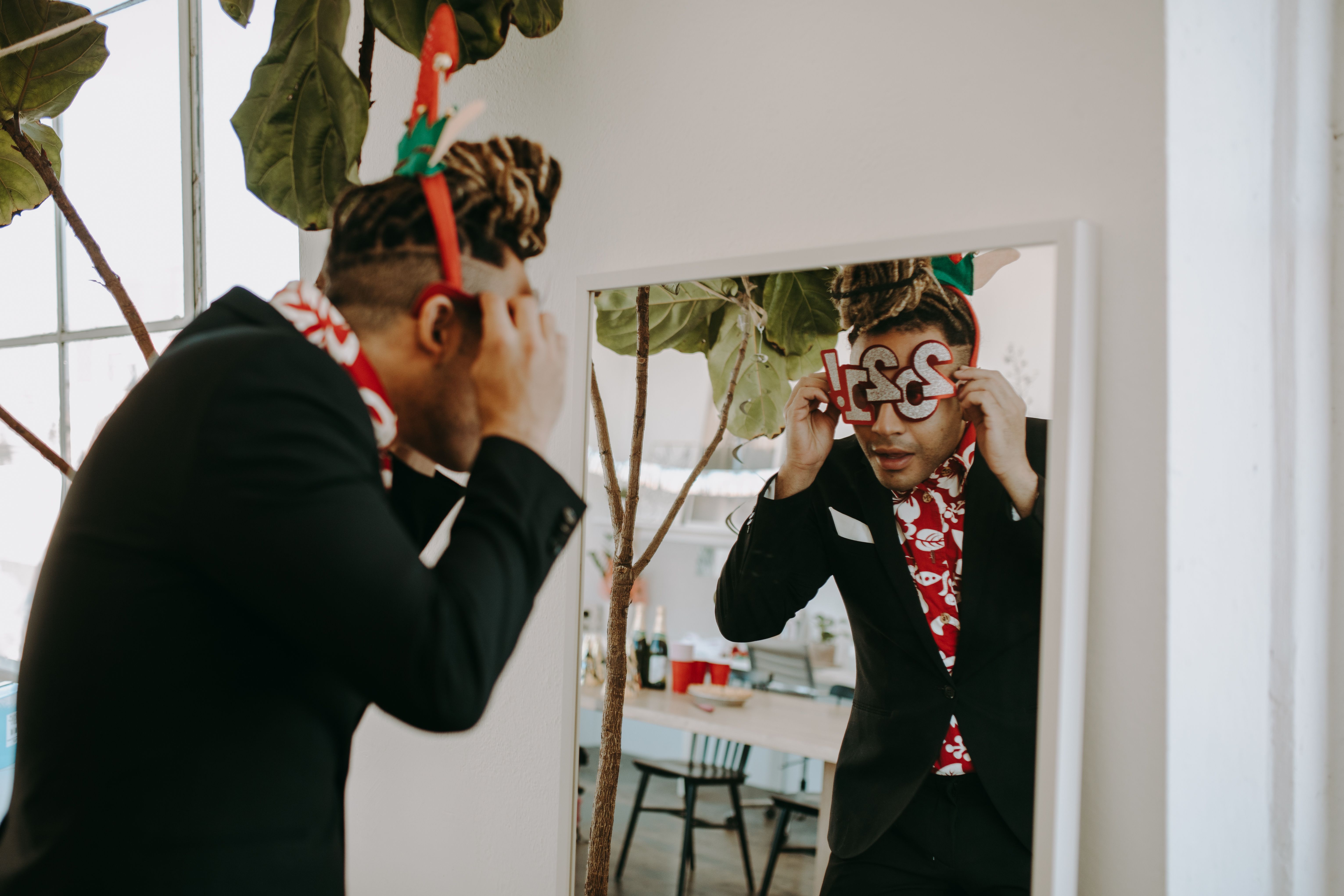 A man adjusting party glasses in front of a mirror