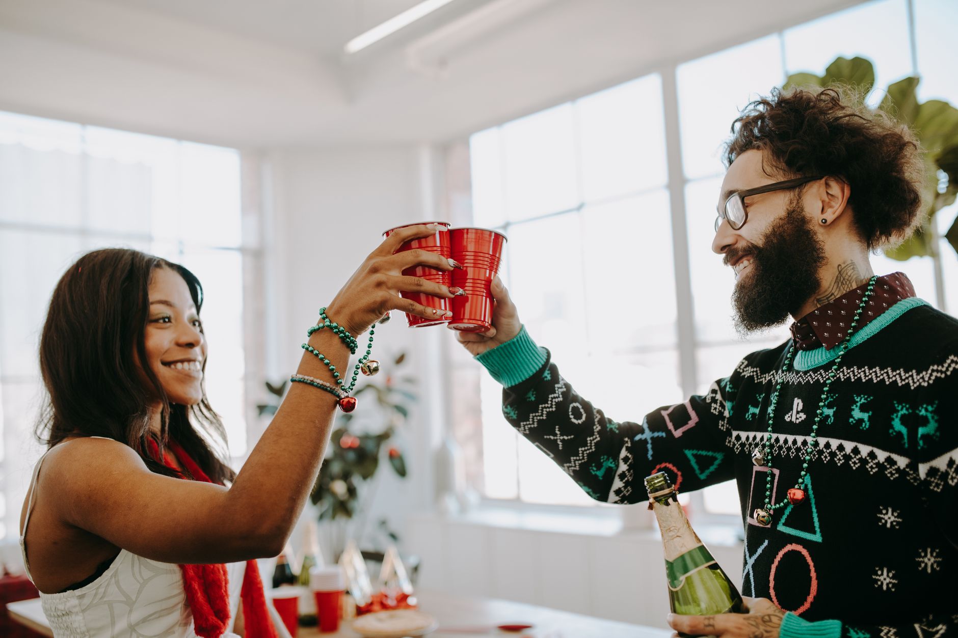 Smiling adults toasting with red cups during a holiday celebration indoors.