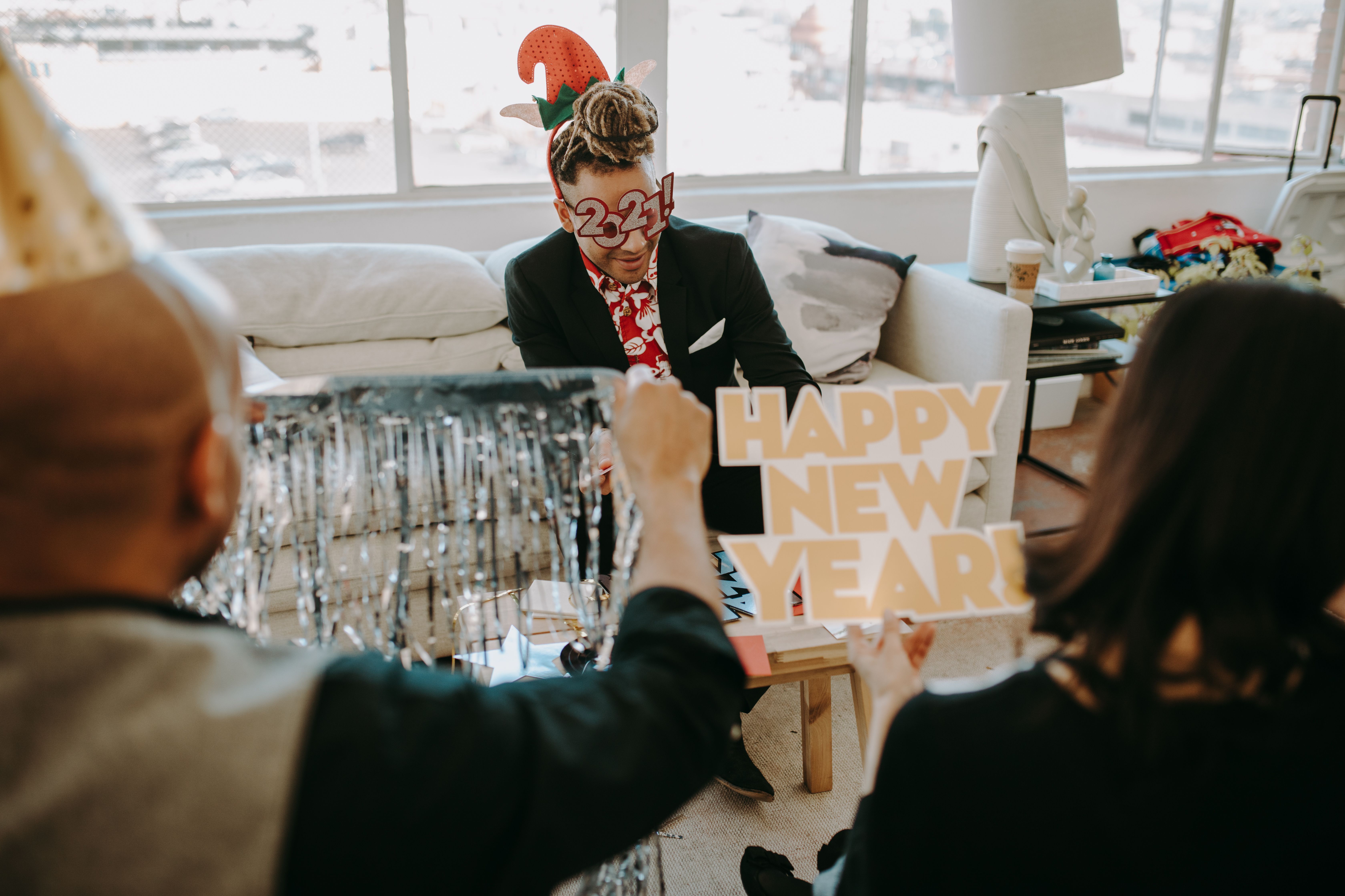 Celebratory New Year's party indoors with festive decor, party hats, and joyful people.