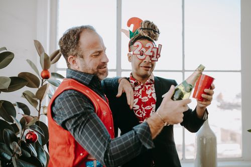 Free Two adults celebrating a festive office holiday party with drinks and joy. Stock Photo