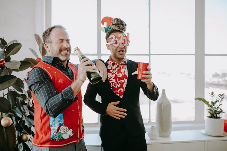 Two Men Holding Drinks While Having Fun