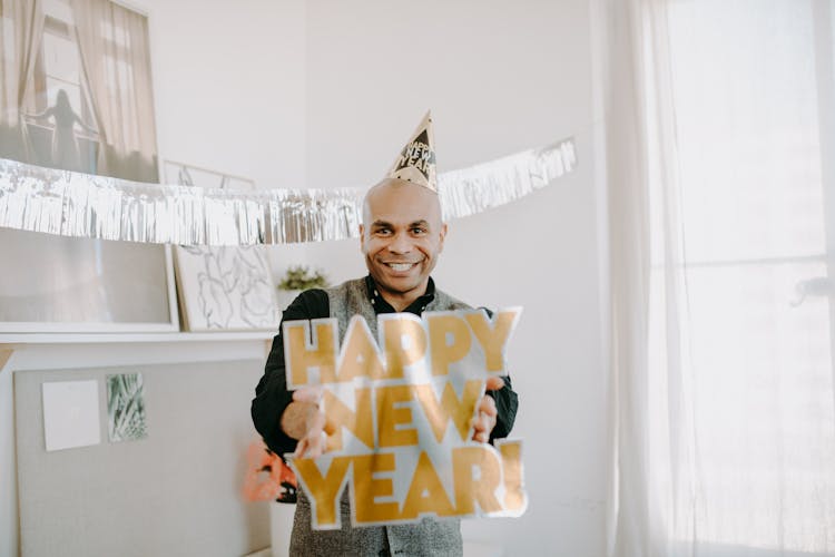 A Man Smiling While Holding A Happy New Year Sign