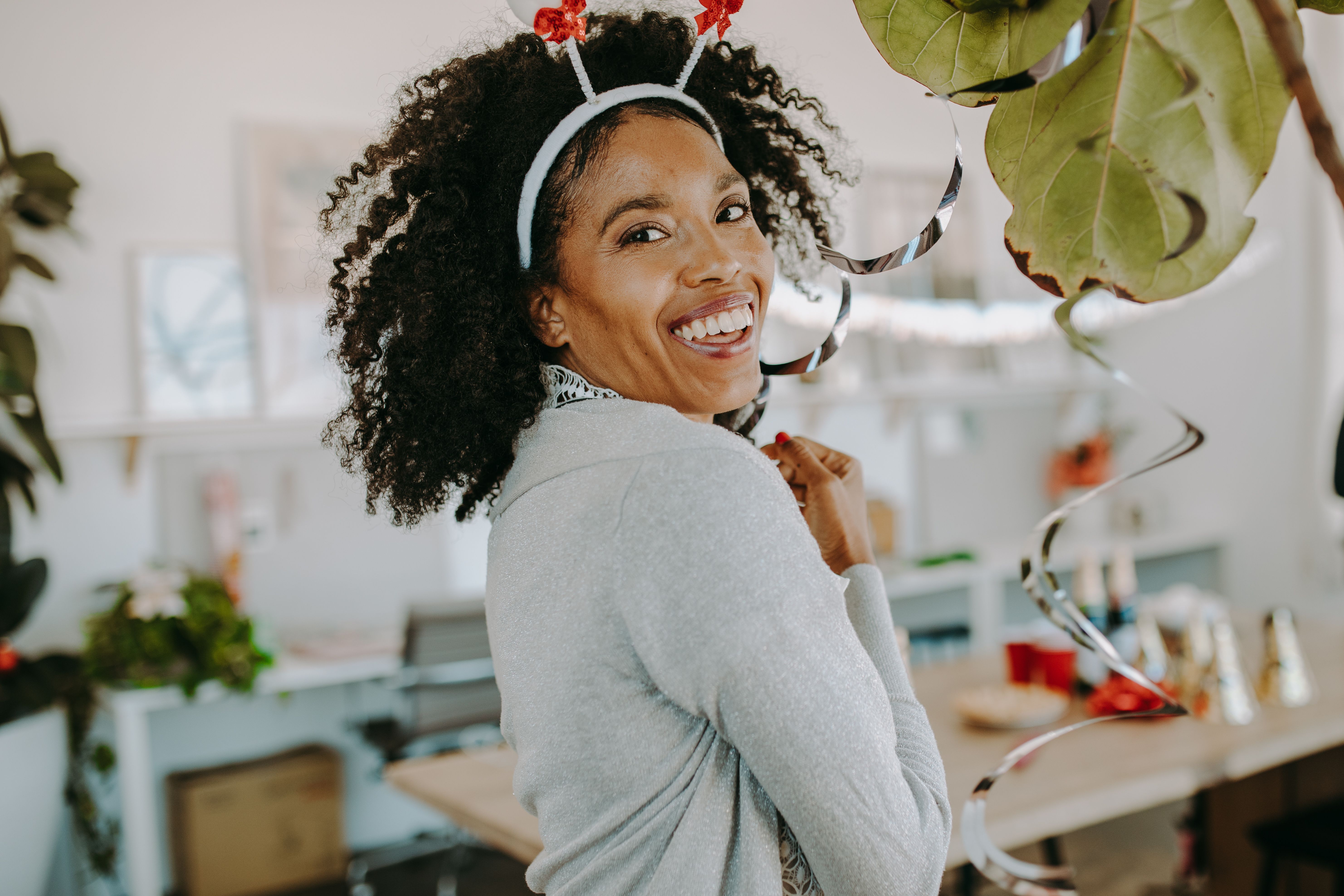 Smiling woman enjoying a festive office holiday party with decorations.