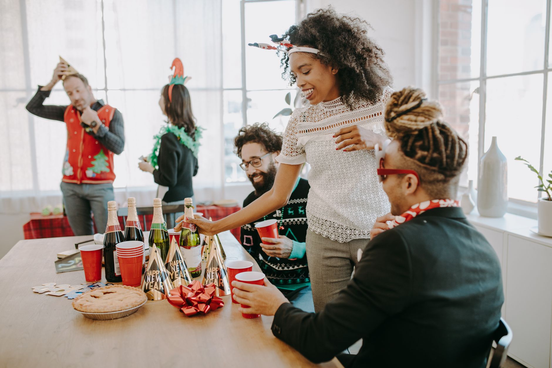 Colleagues enjoy a lively holiday party with drinks and festive decorations.