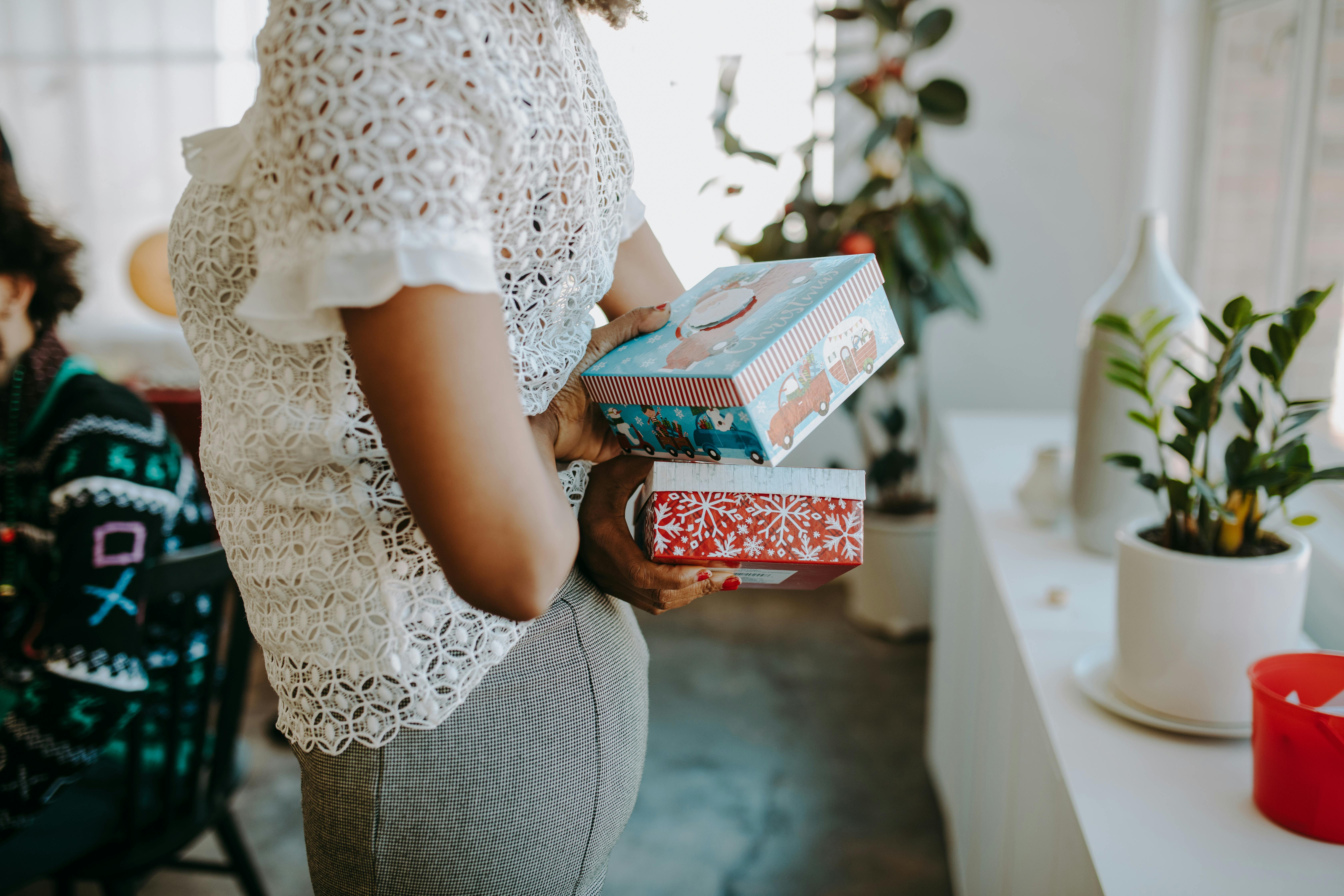 Woman holding Christmas gifts at a holiday gathering in a cozy indoor setting.