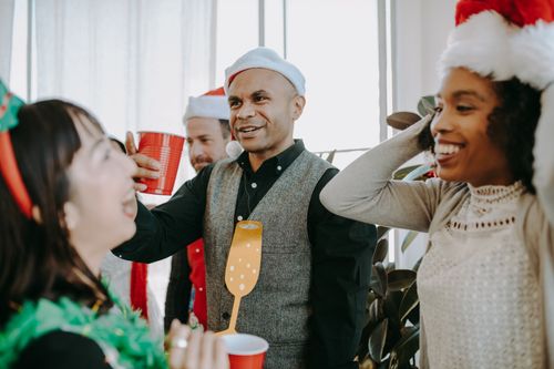 Free Group of colleagues enjoying a festive office party with drinks and holiday hats. Stock Photo