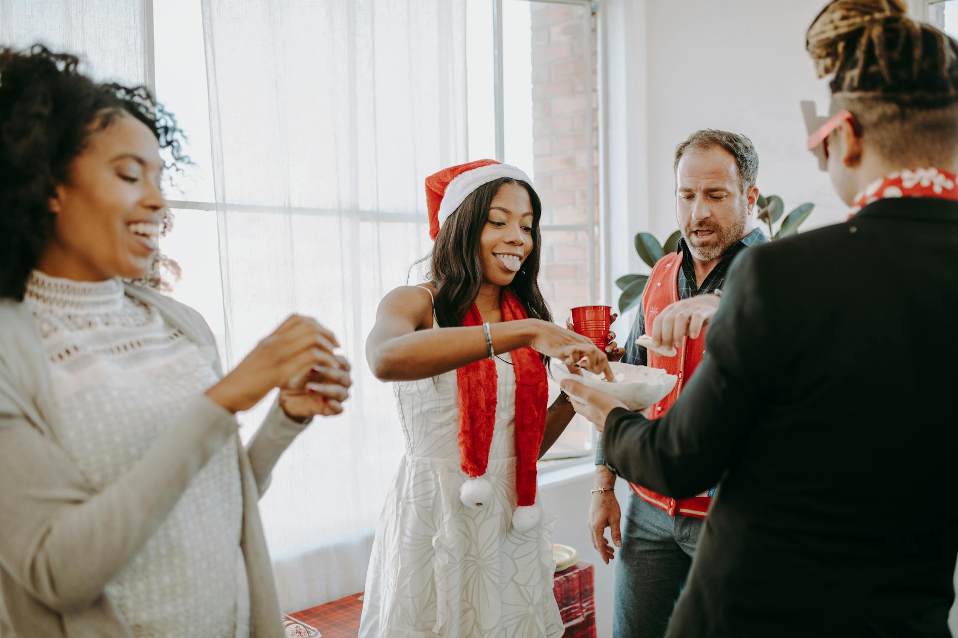 Colleagues enjoying a joyful holiday party in an office setting, sharing snacks and laughter.
