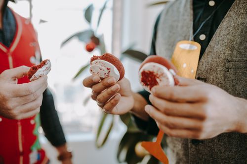 Free Festive close-up of hands holding red and white holiday cookies indoors. Stock Photo