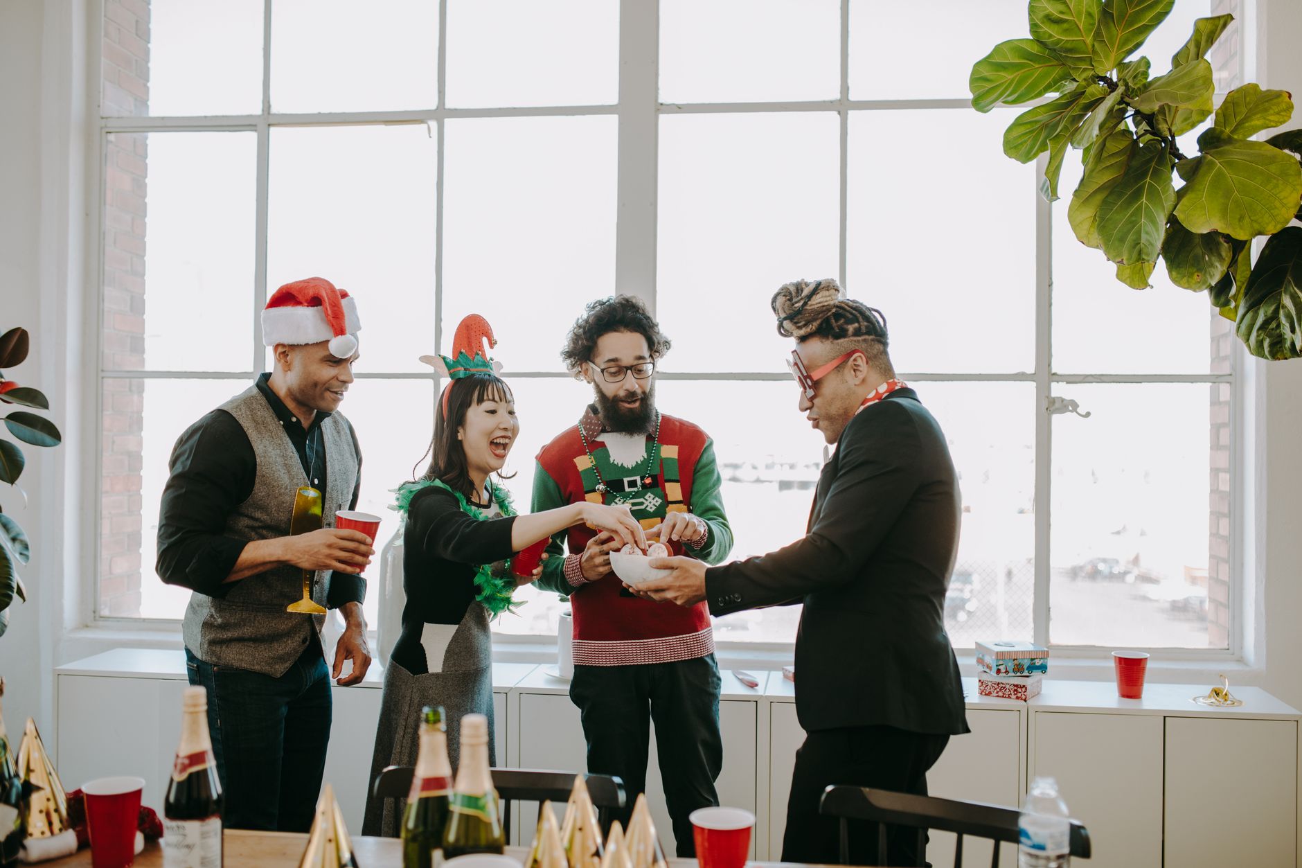 Diverse group of friends celebrating Christmas indoors with drinks and snacks.