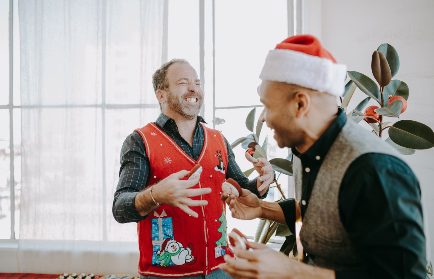 Two friends enjoying a Christmas celebration, wearing festive attire indoors.