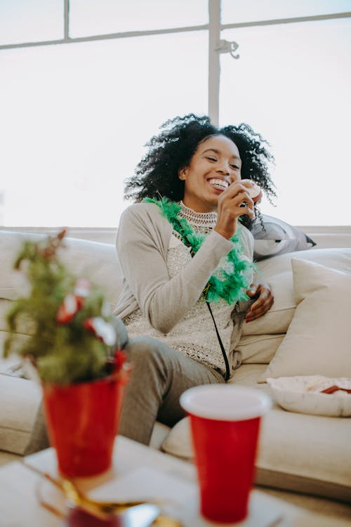 Free A Woman Laughing while Sitting on the Couch Stock Photo