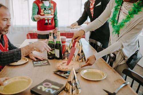 A Man Looking at the Person Slicing a Pie on the Wooden Table