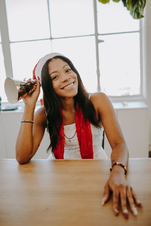 Free Joyful woman in a Santa hat celebrating indoors with a bright smile. Stock Photo