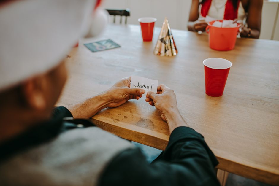 Casual indoor gathering scene with friends holding name card, red cups, and party hats on a wooden table. Casual indoor gathering scene with friends holding name card, red cups, and party hats on a wooden table.