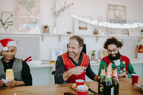 Free Group of friends enjoying a festive gathering with drinks and laughter indoors. Stock Photo