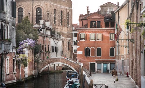 Free A picturesque Venetian canal scene featuring classic architecture, a stone bridge, and a serene atmosphere. Stock Photo