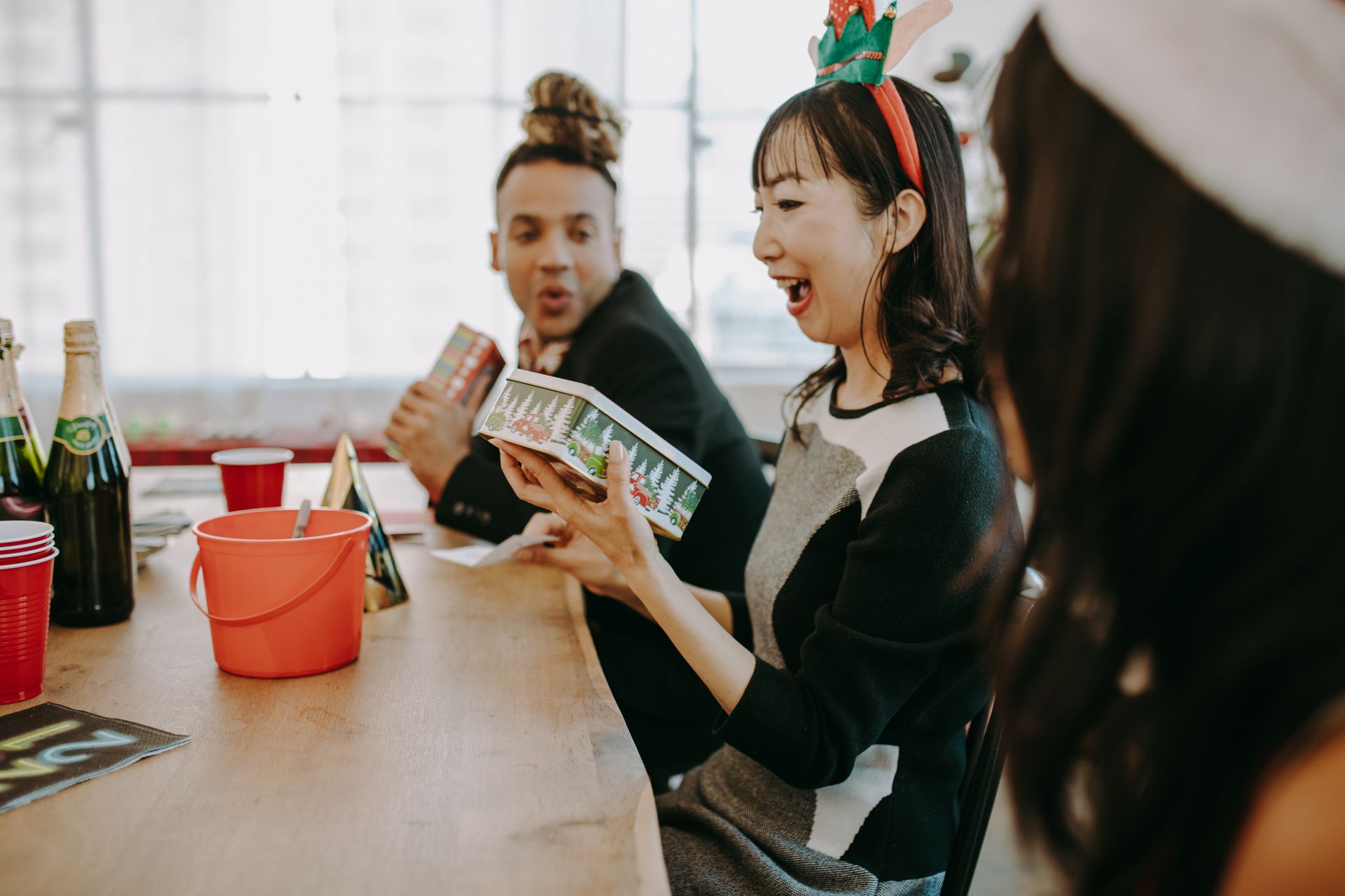 A joyful team enjoys a Christmas party with gifts at an office setting.