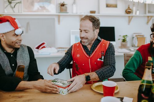 Free Colleagues exchanging gifts during an office Christmas celebration, showcasing holiday joy and festivity. Stock Photo