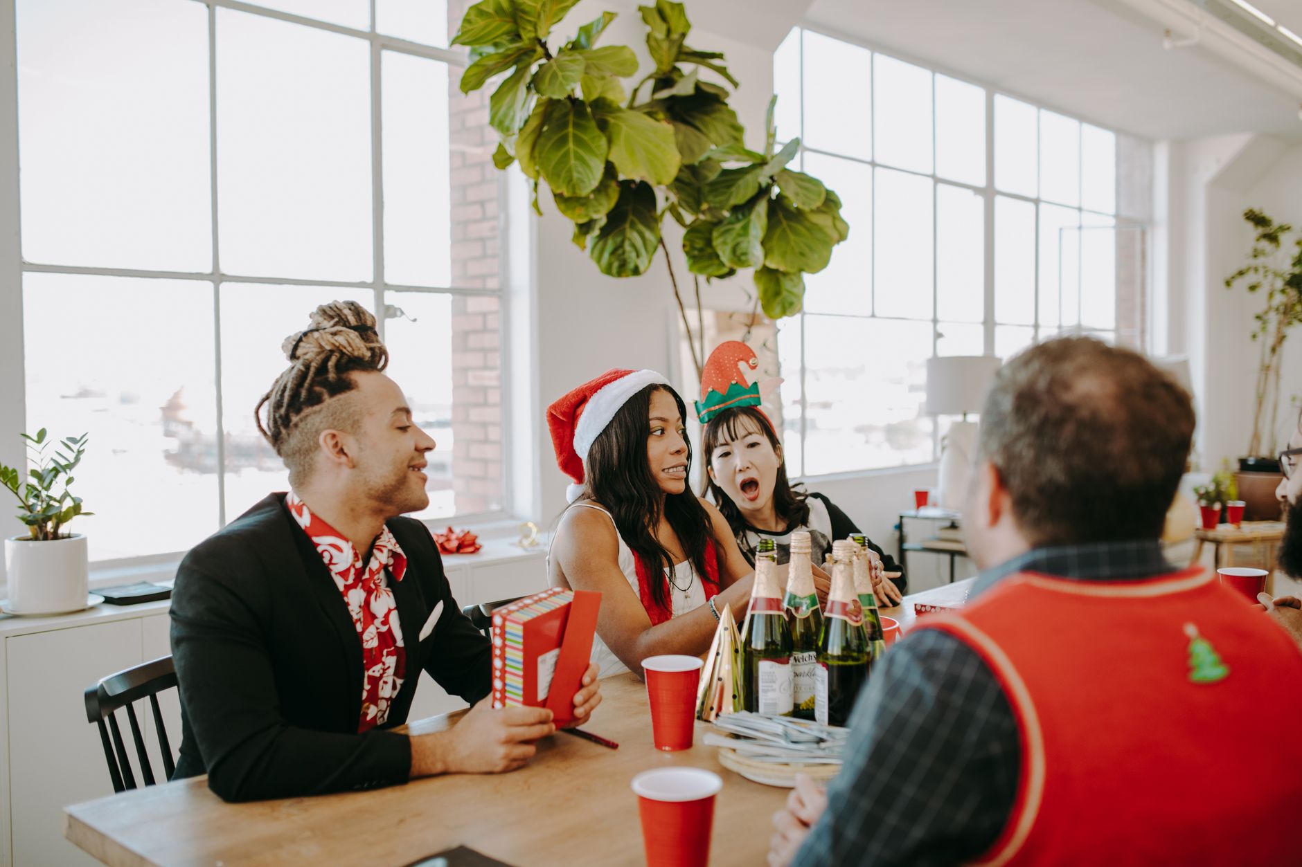 A diverse group of friends celebrating Christmas indoors with festive drinks and decorations.