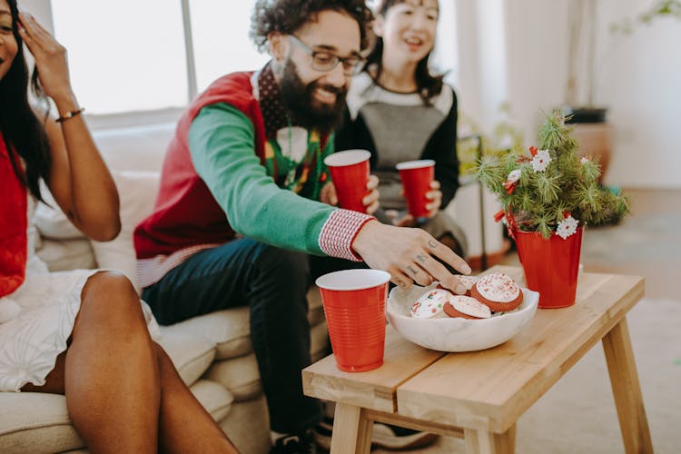 Man Sitting On Sofa While Getting A Cookie From A Bowl