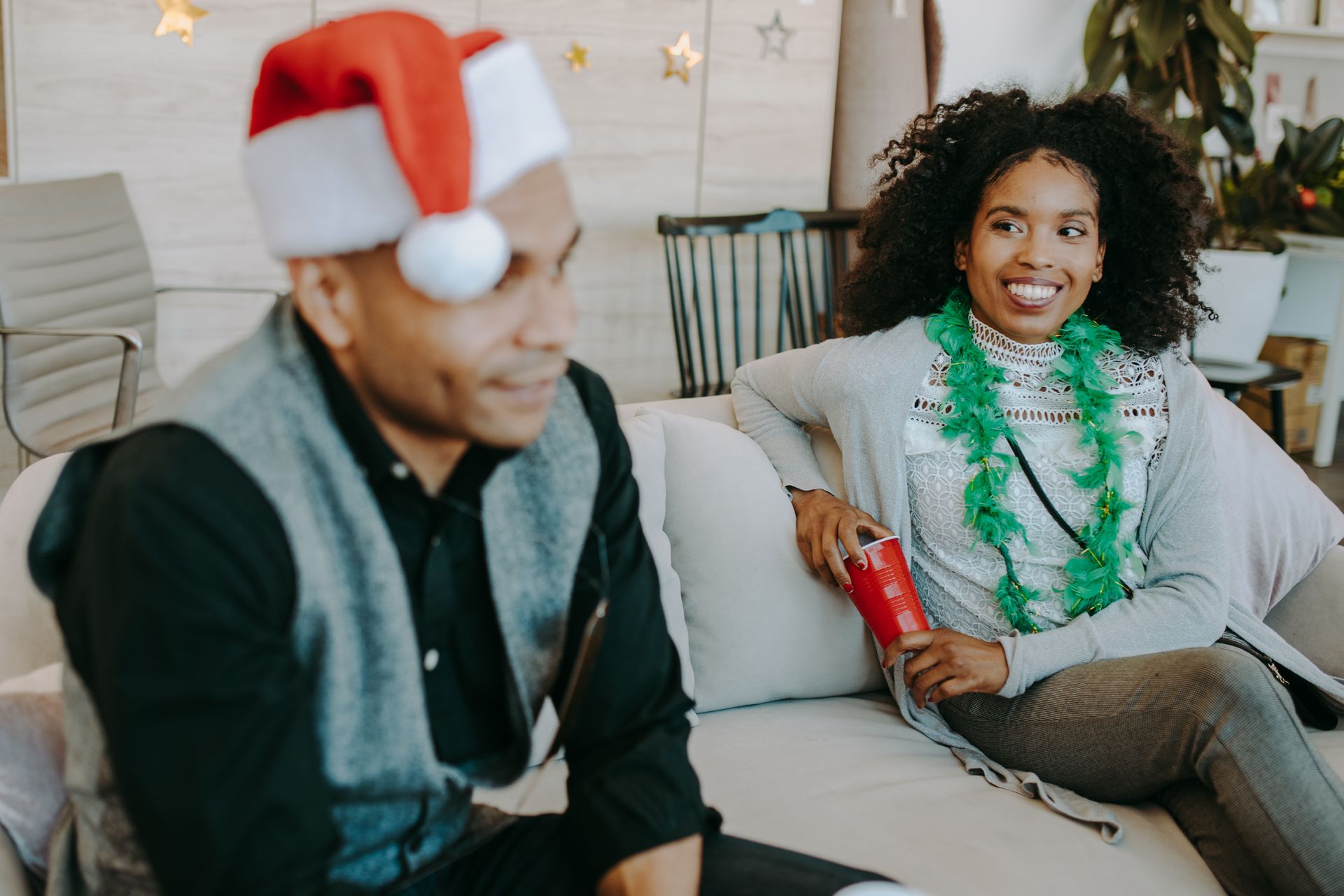 Smiling couple enjoying a festive holiday party indoors with decorations.