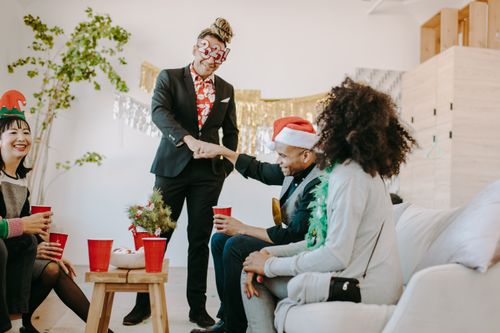 Free Group of friends enjoying a Christmas party indoors, exchanging fist bumps and smiles with festive decorations. Stock Photo