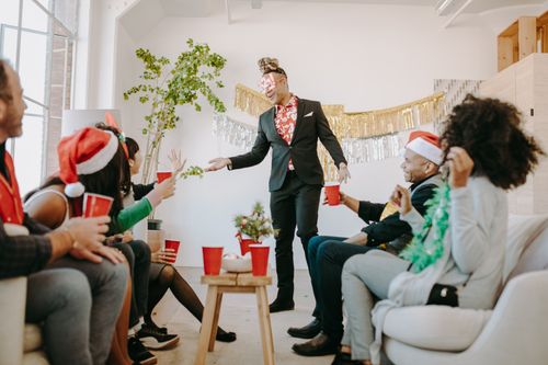 Free Colleagues enjoying a Christmas office party with drinks and holiday decor. Stock Photo