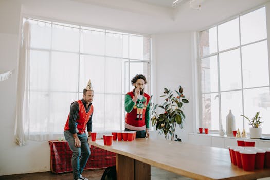 Adults playing beer pong during a festive office holiday party with fun and laughter.
