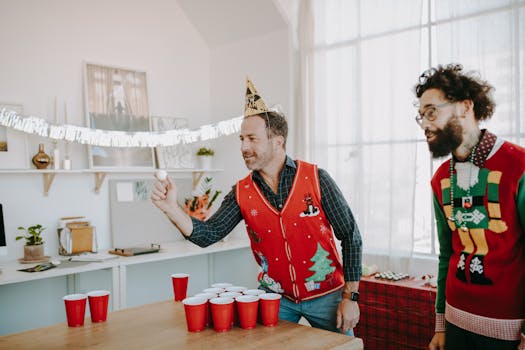 Colleagues play beer pong at a joyful office holiday party in festive attire.