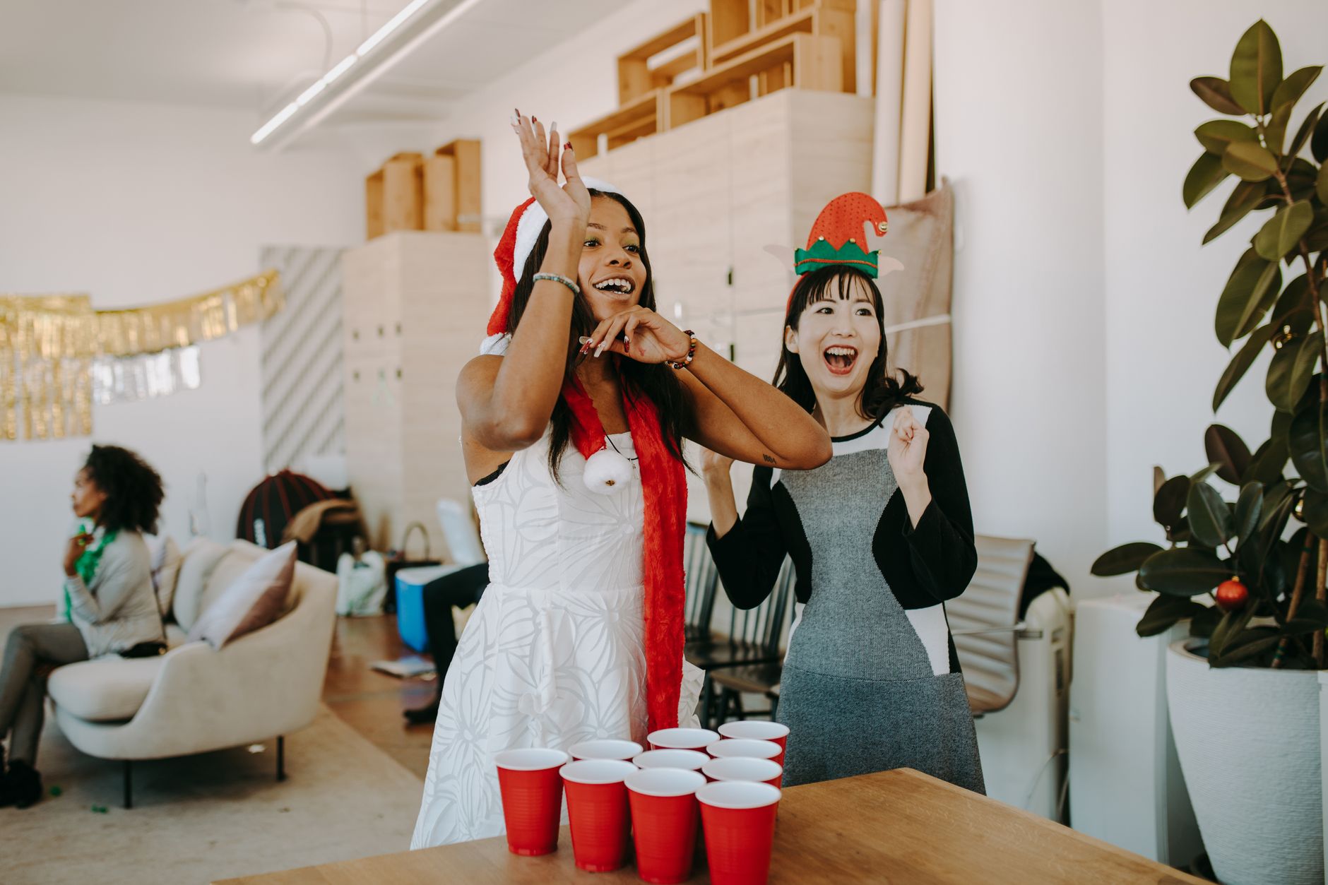 Adults enjoying a fun Christmas party with festive games and decorations in an office setting.
