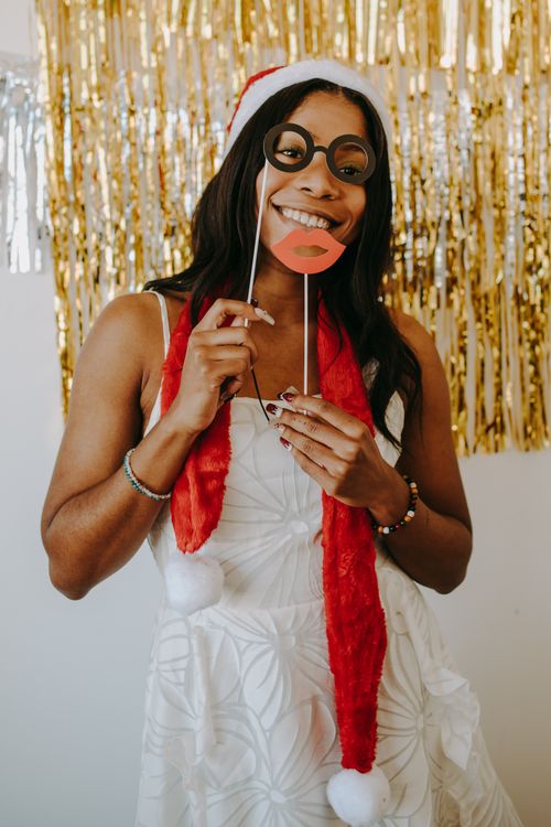 Free Black woman in festive attire with props at a Christmas party, celebrating with a cheerful spirit. Stock Photo