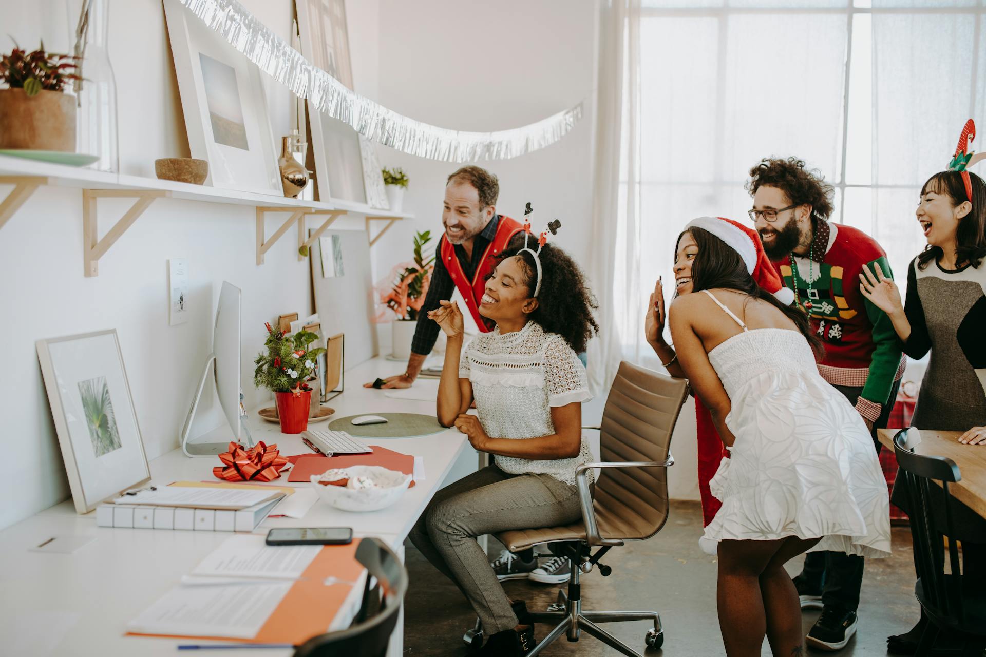 Diverse group enjoying a virtual holiday party in a decorated office environment.