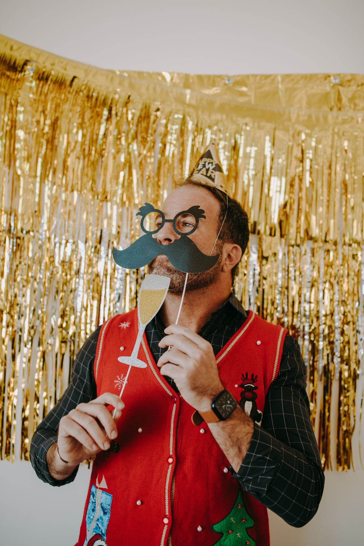 21st birthday party ideas with a guest holding photo booth props in front of a gold backdrop for a photo booth party