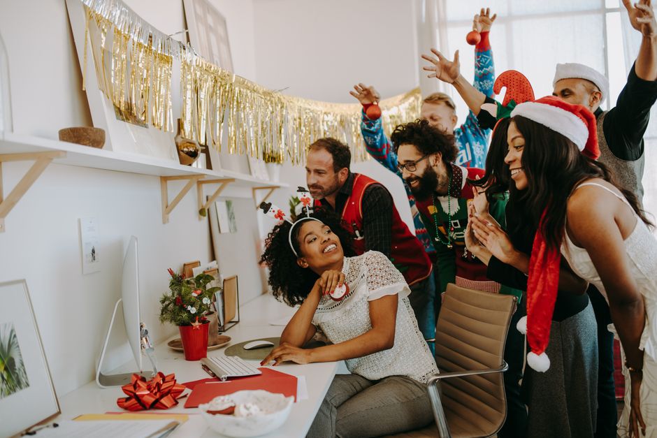 Group of coworkers in Christmas attire celebrating the holidays at the office.