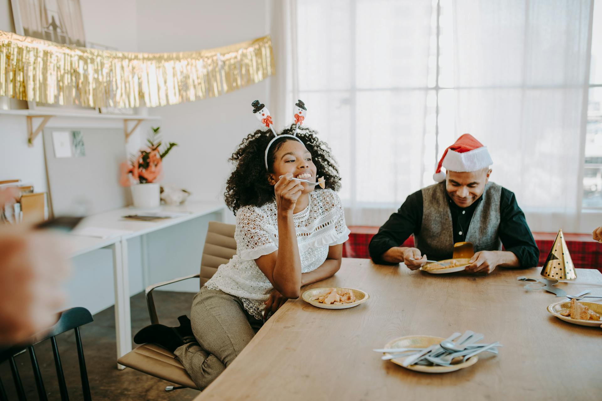 Colleagues enjoying a festive office party with food and holiday decorations.