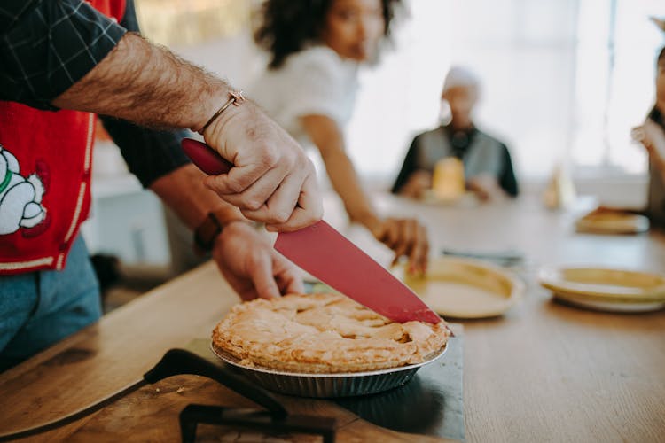 Person Slicing A Pie On The Table