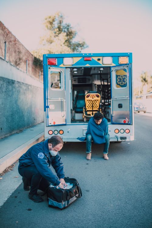 Free EMT providing care by an ambulance on a sunny roadside Stock Photo