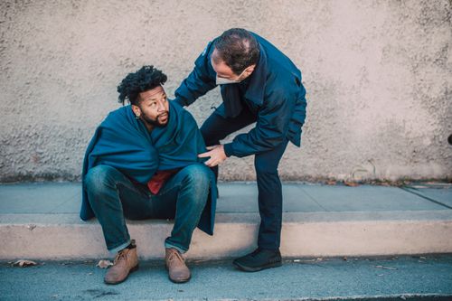 Free Emergency medical technician aids a man seated on the street, showcasing assistance and care. Stock Photo