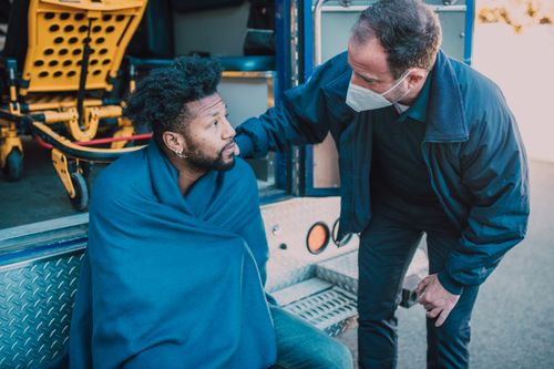 Free A paramedic talks to a patient covered in a blanket outside an ambulance, offering reassurance. Stock Photo