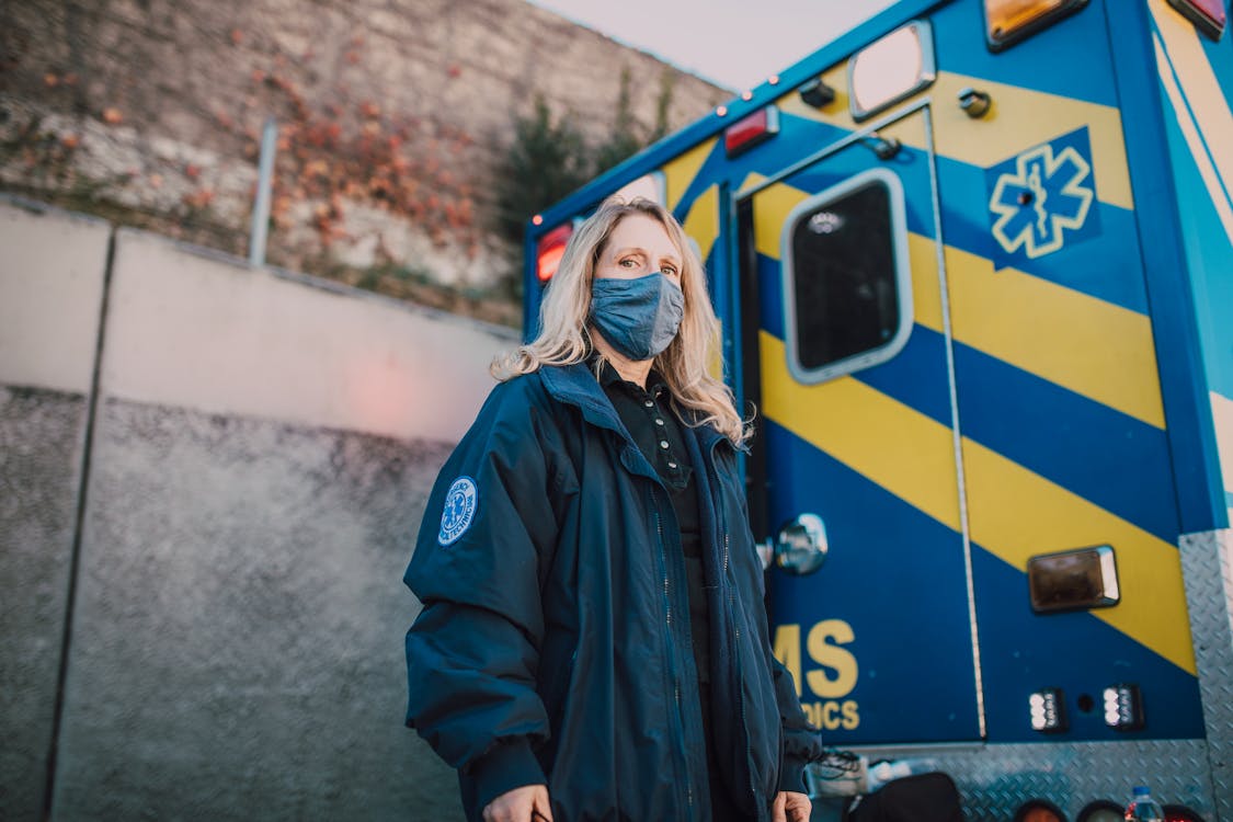 Woman Wearing a Mask Standing Behind an Ambulance